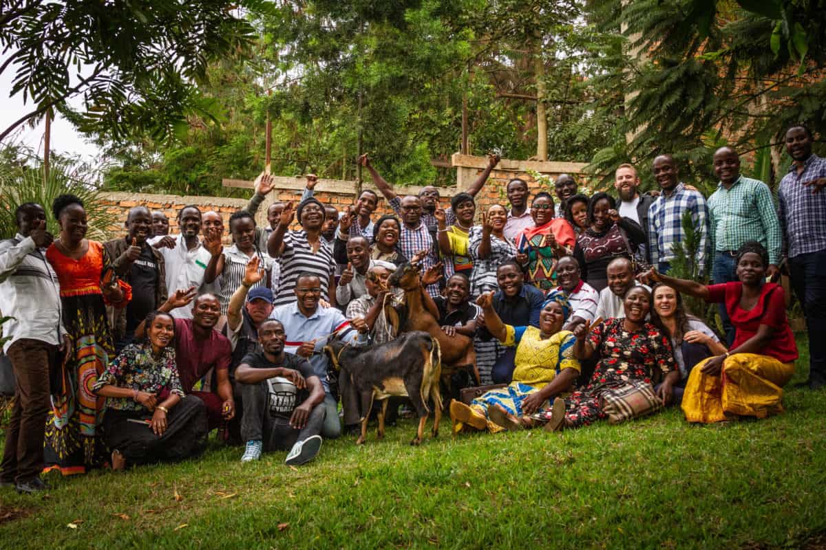 A group photograph of the staff of Eastern Congo Initiative on a lush green lawn, with two goats. Photo: Gerry Kahashy